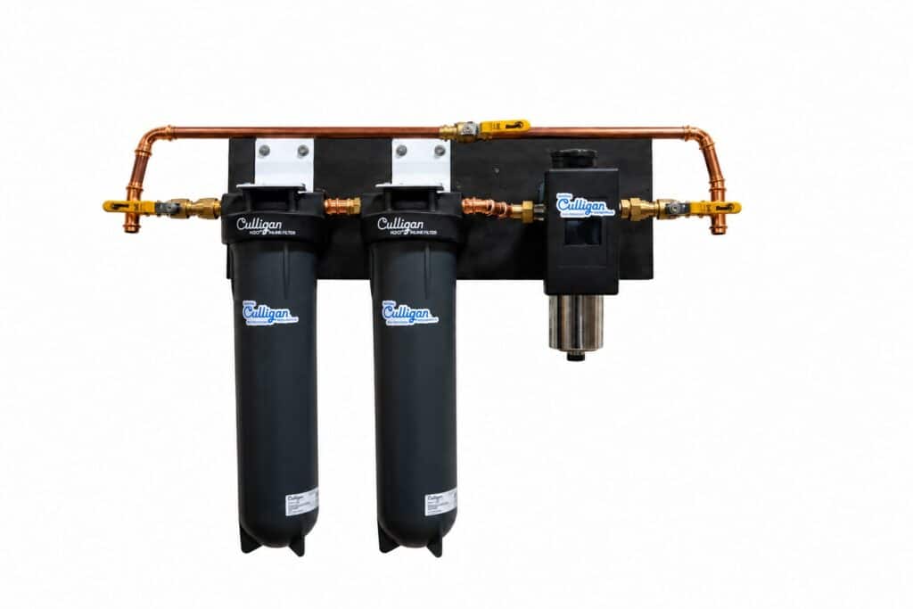 Two black Culligan water filters and one smaller Culligan filter mounted on a black panel with copper plumbing and yellow-handled valves.